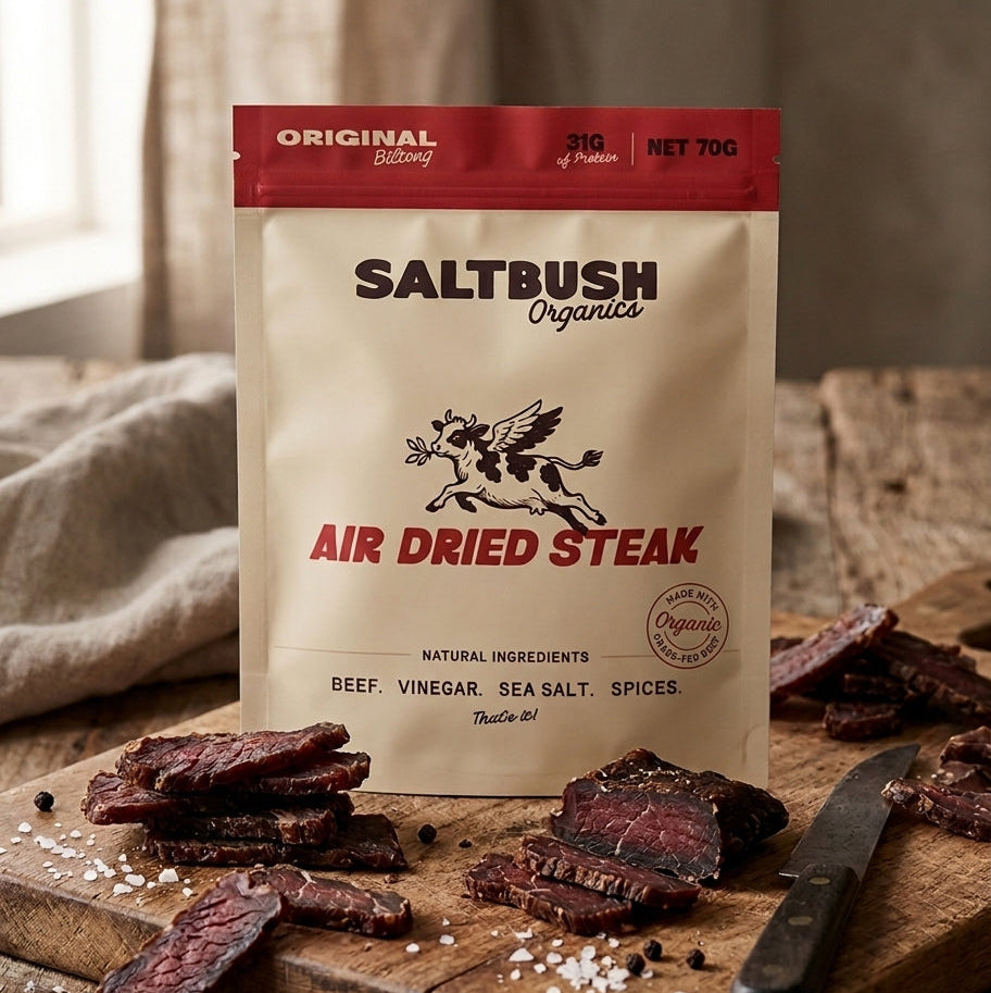 Saltbush Organics air dried steak packaging on a wooden cutting board with air dried steak slices.